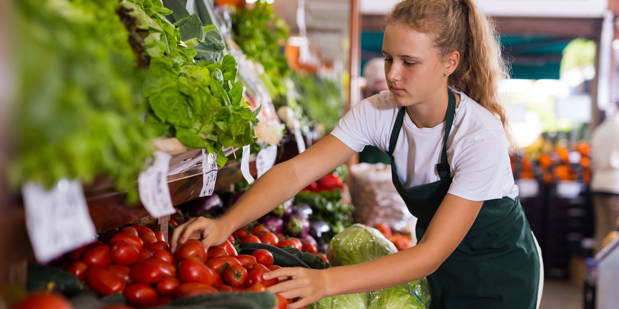 Young woman with apron organizing tomatoes. 
