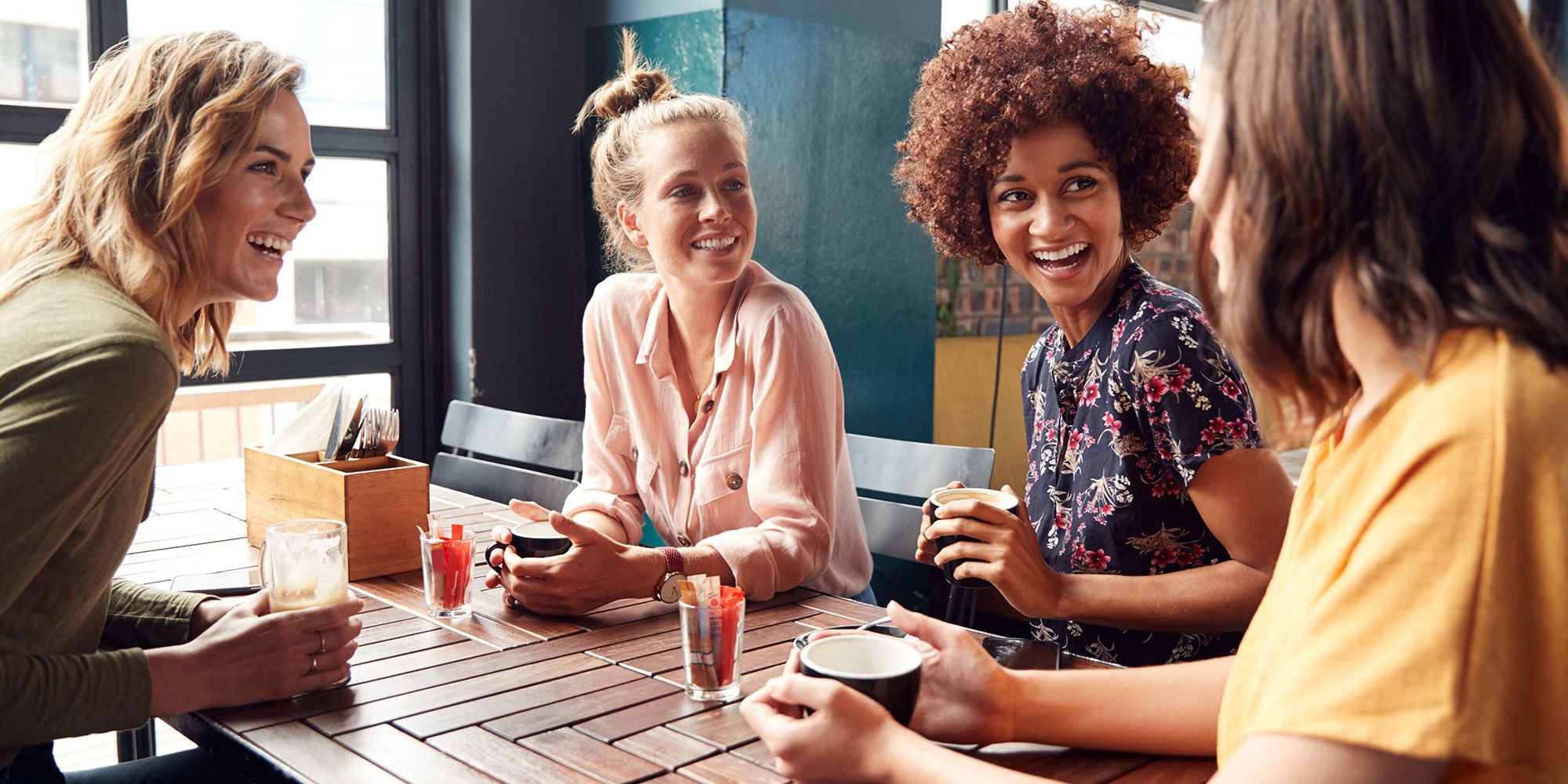 A group of young women having different beverages together.