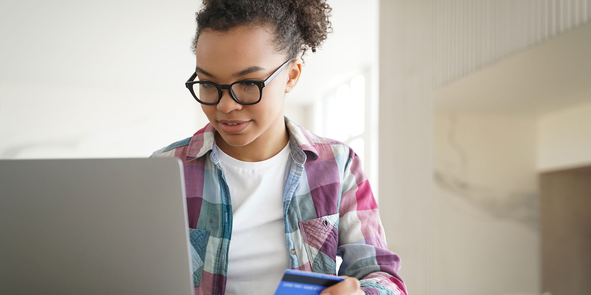 Girl with a credit card in her hand, looking at her laptop.