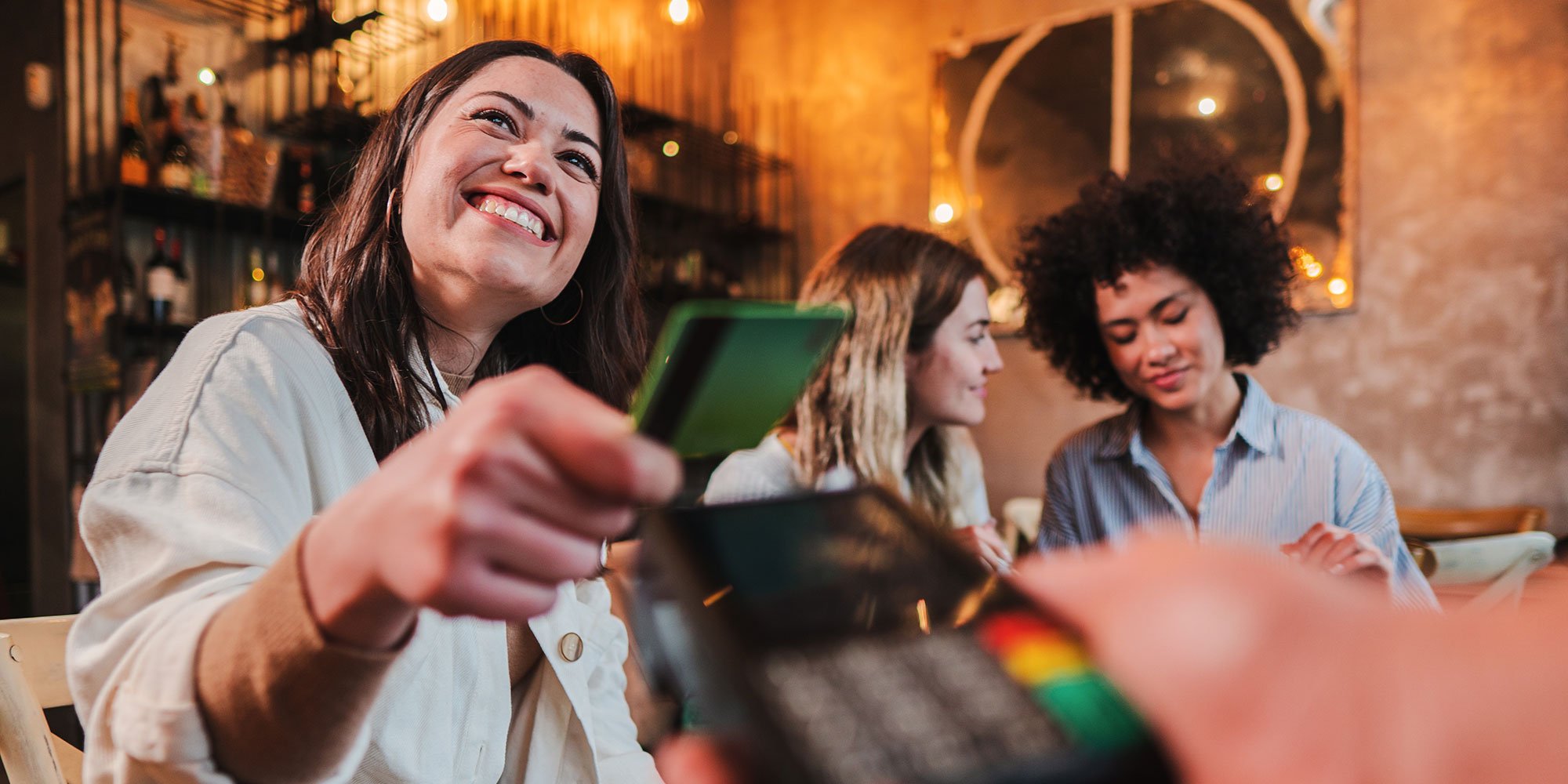 Woman handing credit card for payment, smiling.