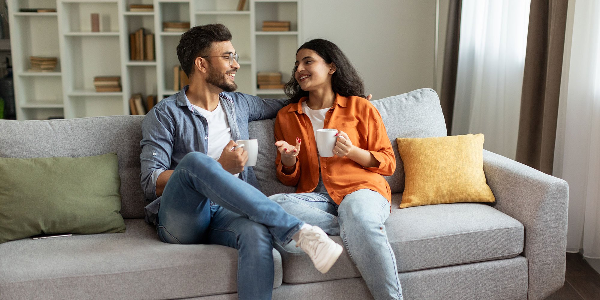 Couple on the couch talking with coffee mugs